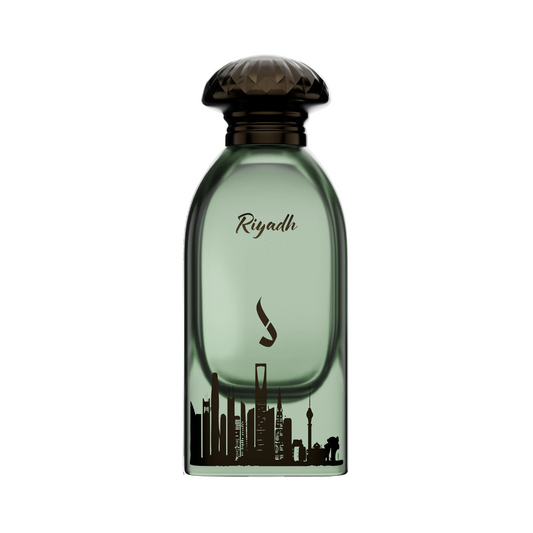 A bottle of Riyadh perfume with a translucent green glass body, a dark brown textured cap, and a black silhouette of the Riyadh skyline printed on the front.